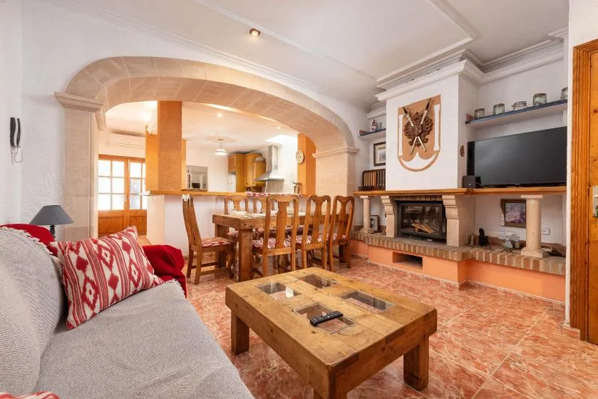 Sala de estar y comedor con zona de asientos, mesa de madera y chimenea.