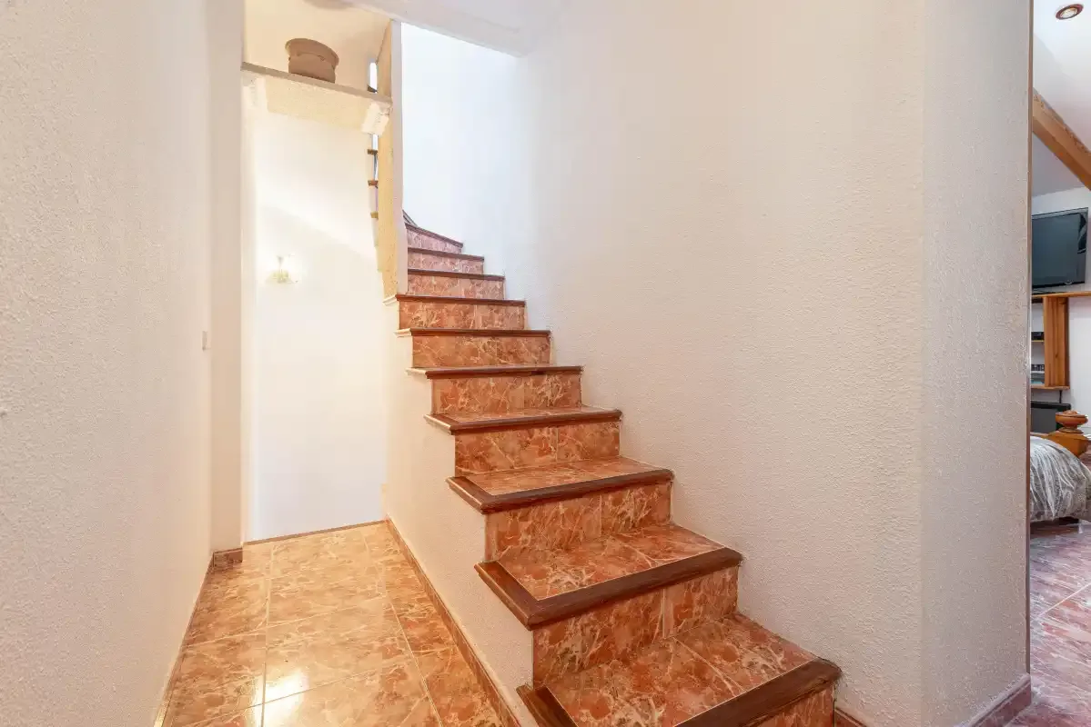 A tiled staircase rises through a bright interior hallway.