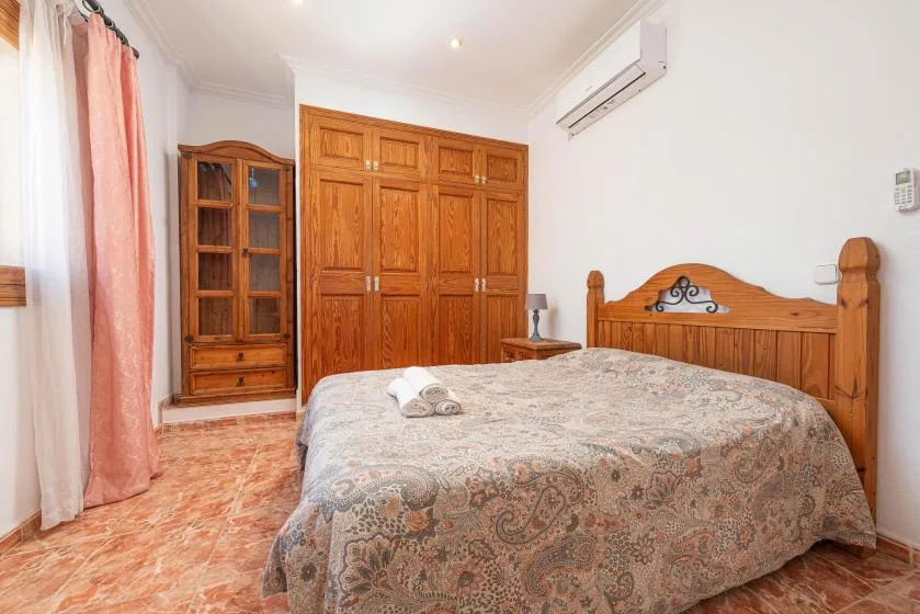 A bedroom with a wooden bed, patterned bedding, and a large wardrobe.