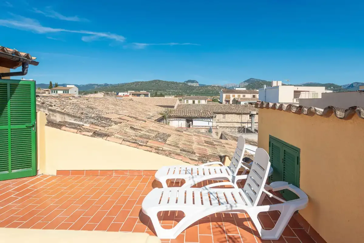 Rooftop terrace with white seating and views over nearby buildings.
