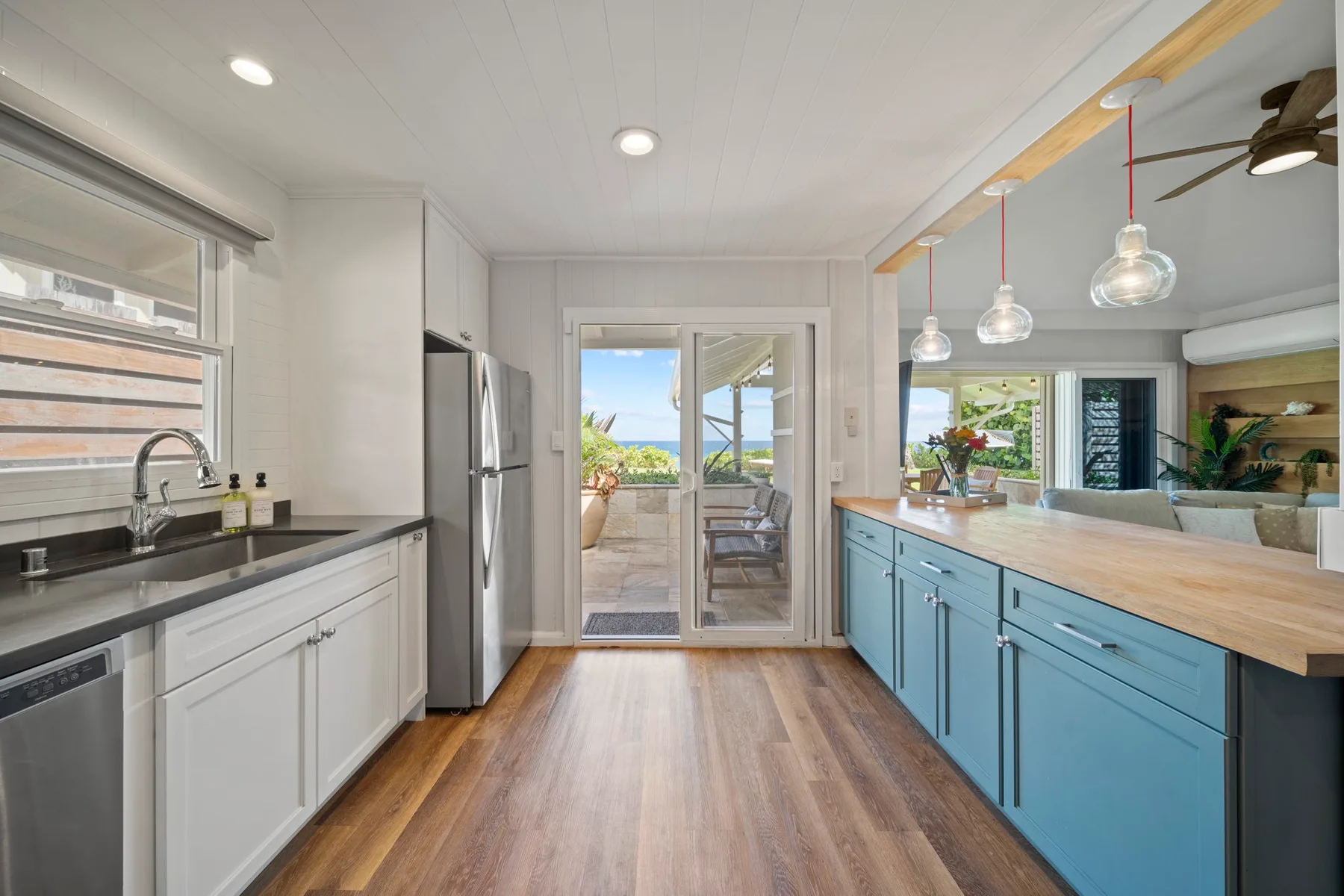 Una cocina luminosa con una isla larga y puertas de vidrio que dan a un patio.