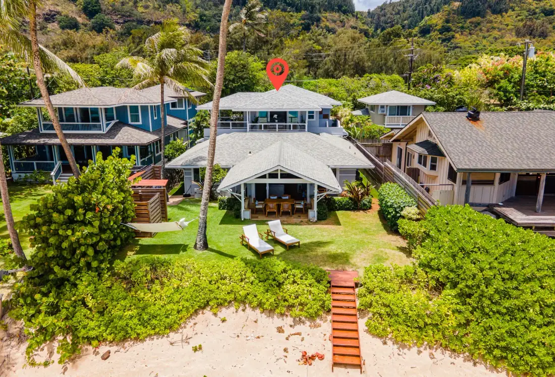 A beachfront property with several buildings, green landscaping, and steps leading to the sand.
