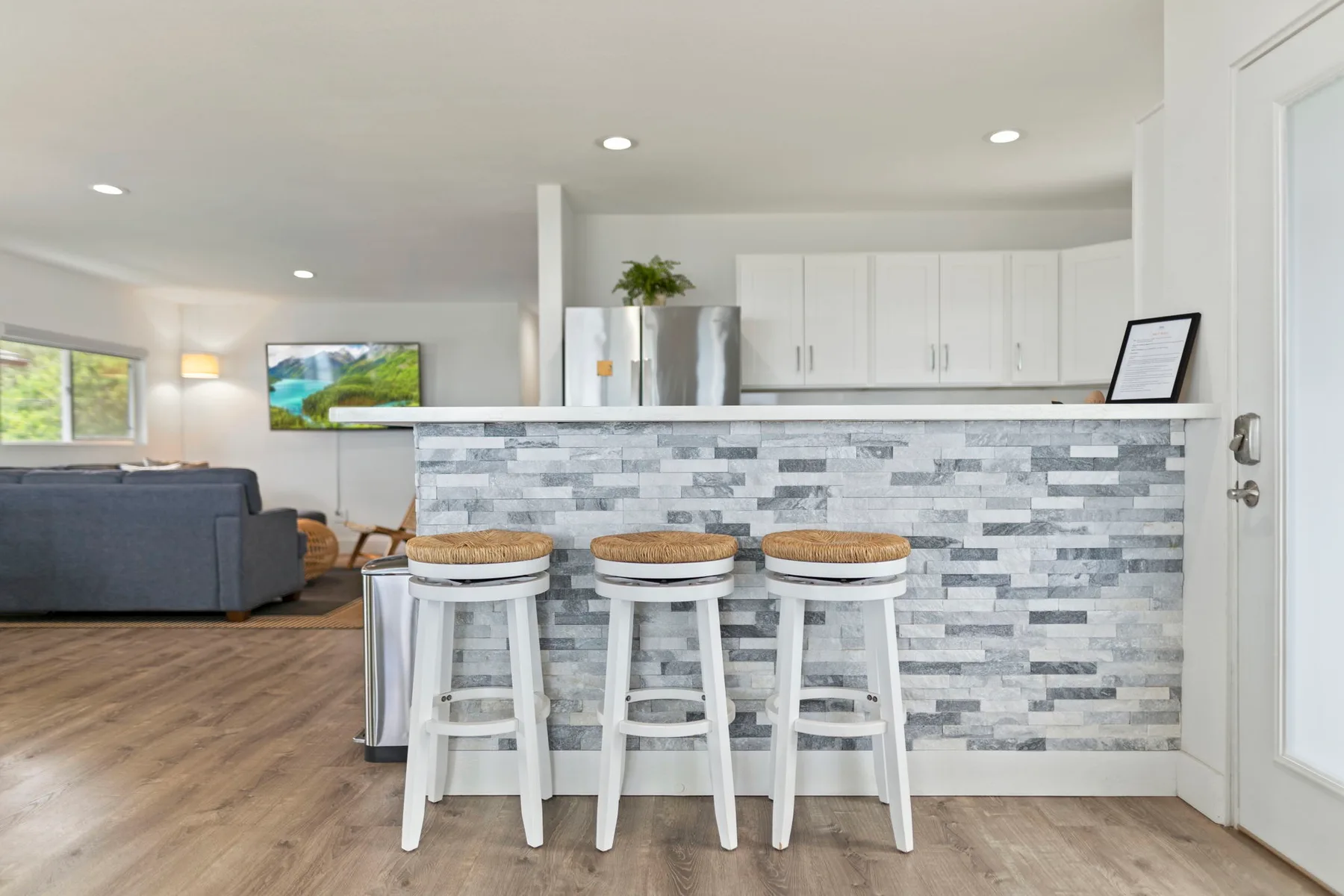 Una sala de estar de concepto abierto y cocina con una barra y taburetes.