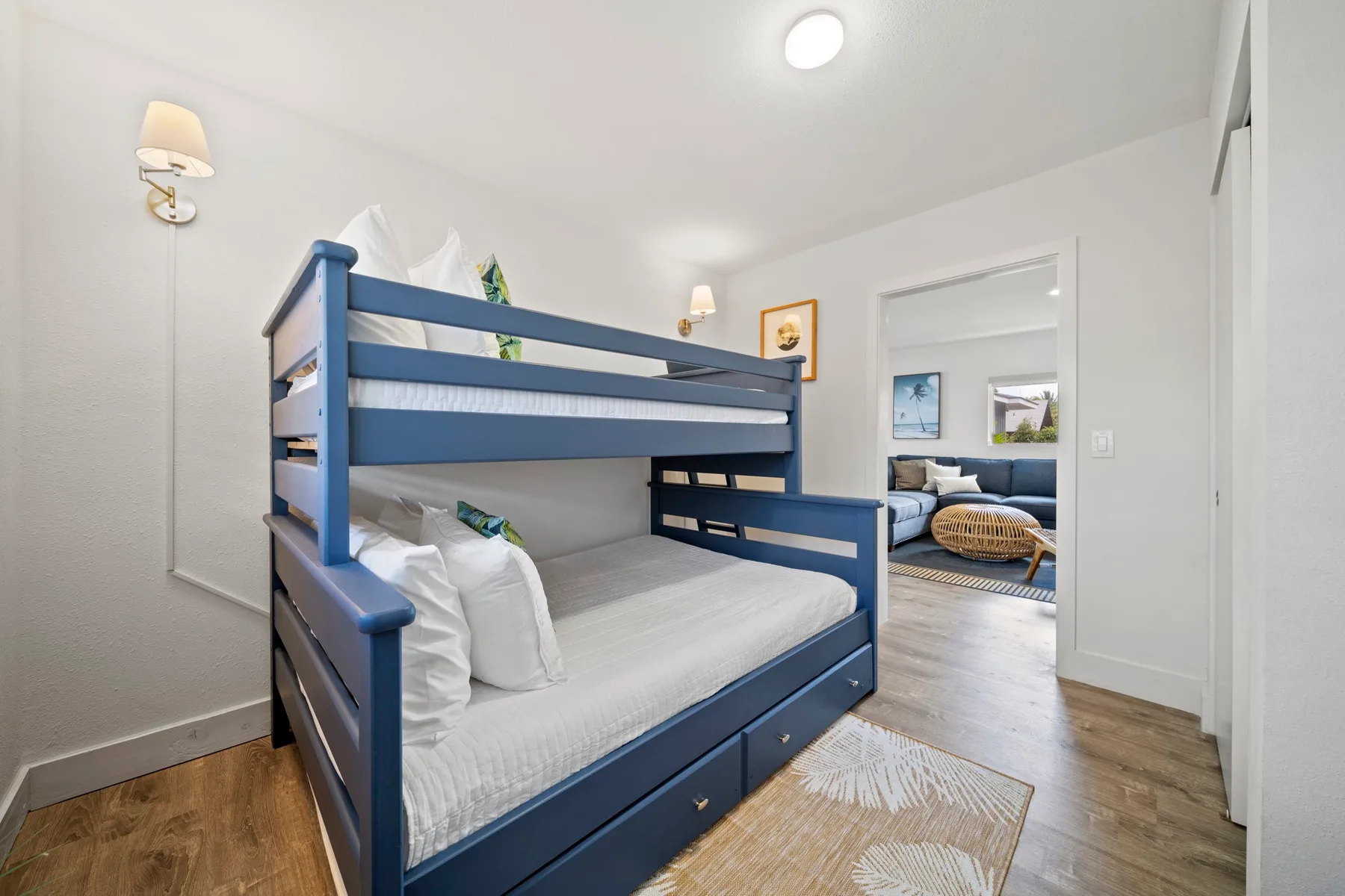 Un dormitorio con una litera azul y una puerta abierta a otra habitación.