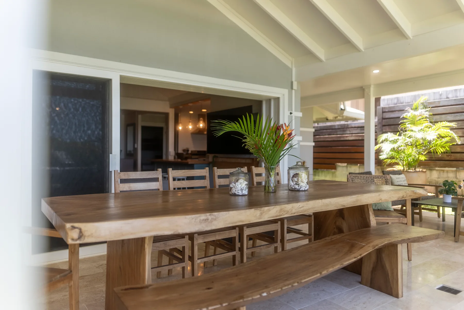 Comedor exterior cubierto con una larga mesa de madera y un banco.