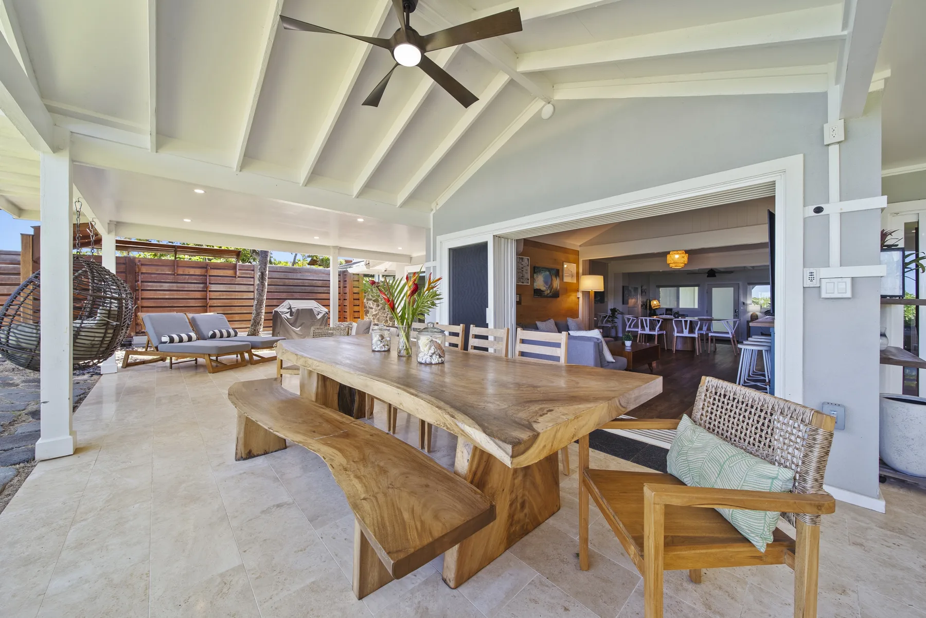 Comedor en un patio cubierto con una larga mesa de madera y una sala contigua.