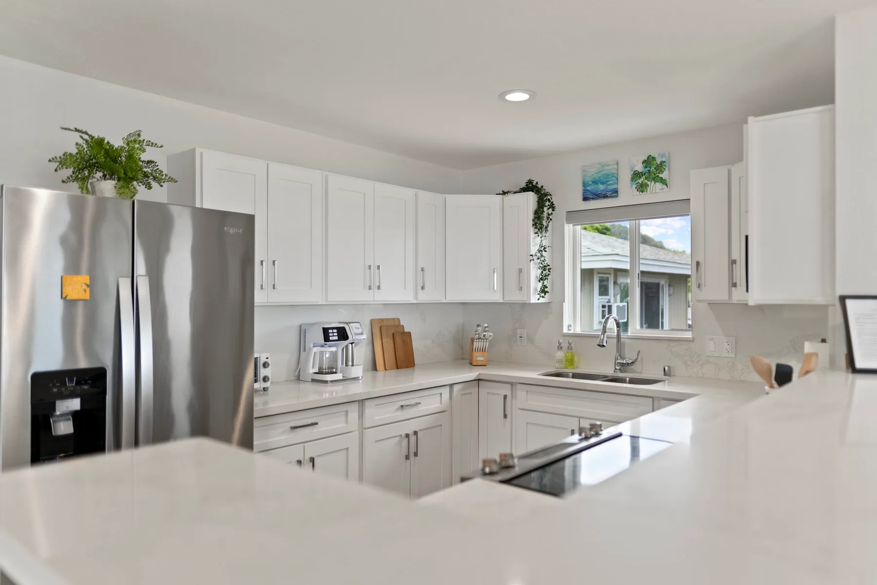 Una cocina luminosa con gabinetes blancos, electrodomésticos de acero inoxidable y una isla central.