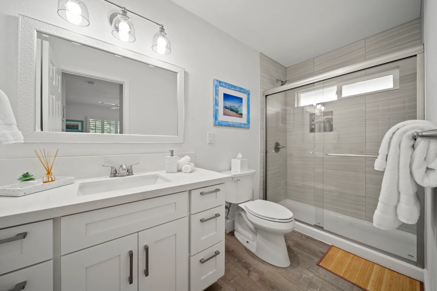 Un baño luminoso con un tocador largo y una ducha de vidrio.