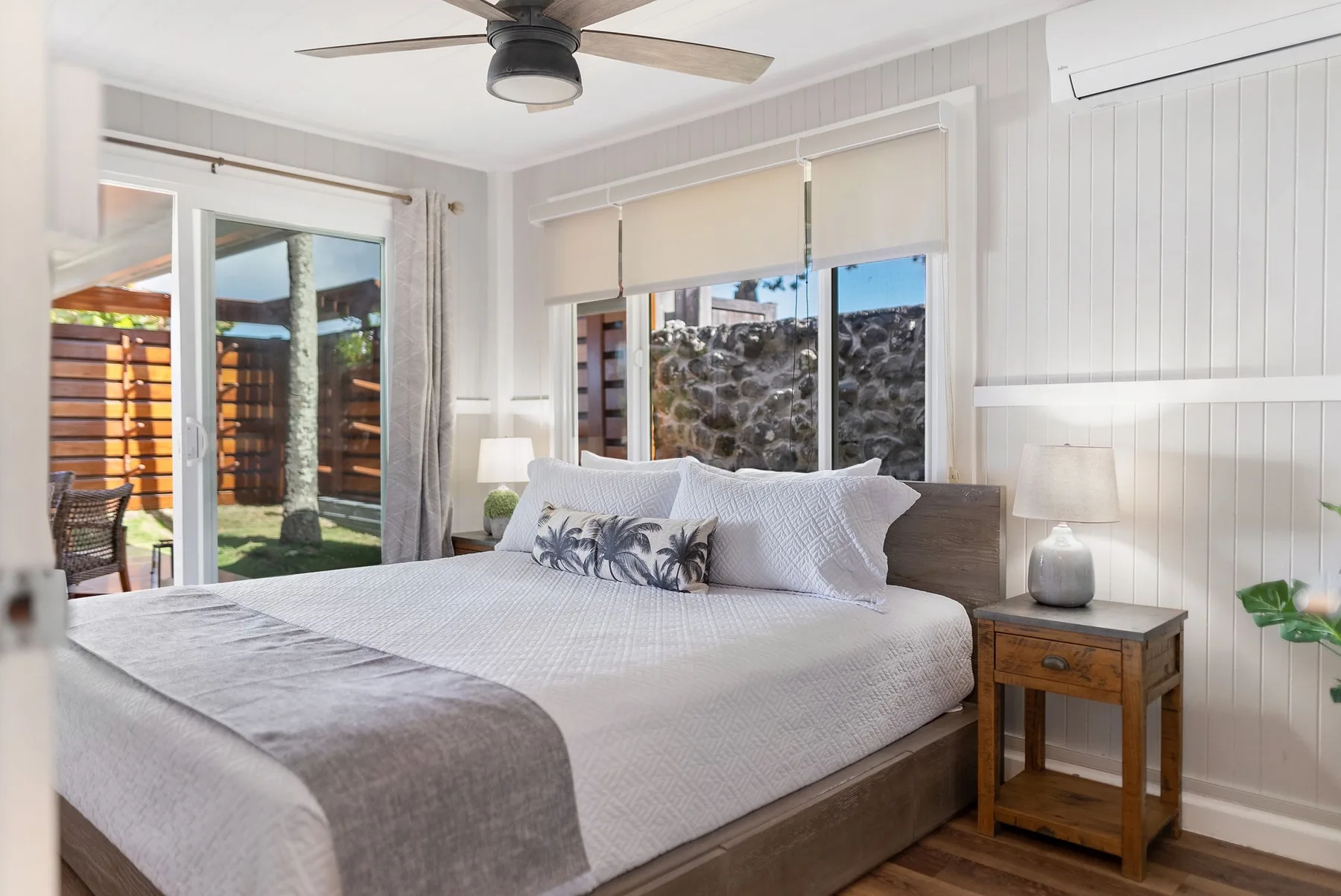 Un dormitorio luminoso con una cama tendida y un ventilador de techo.