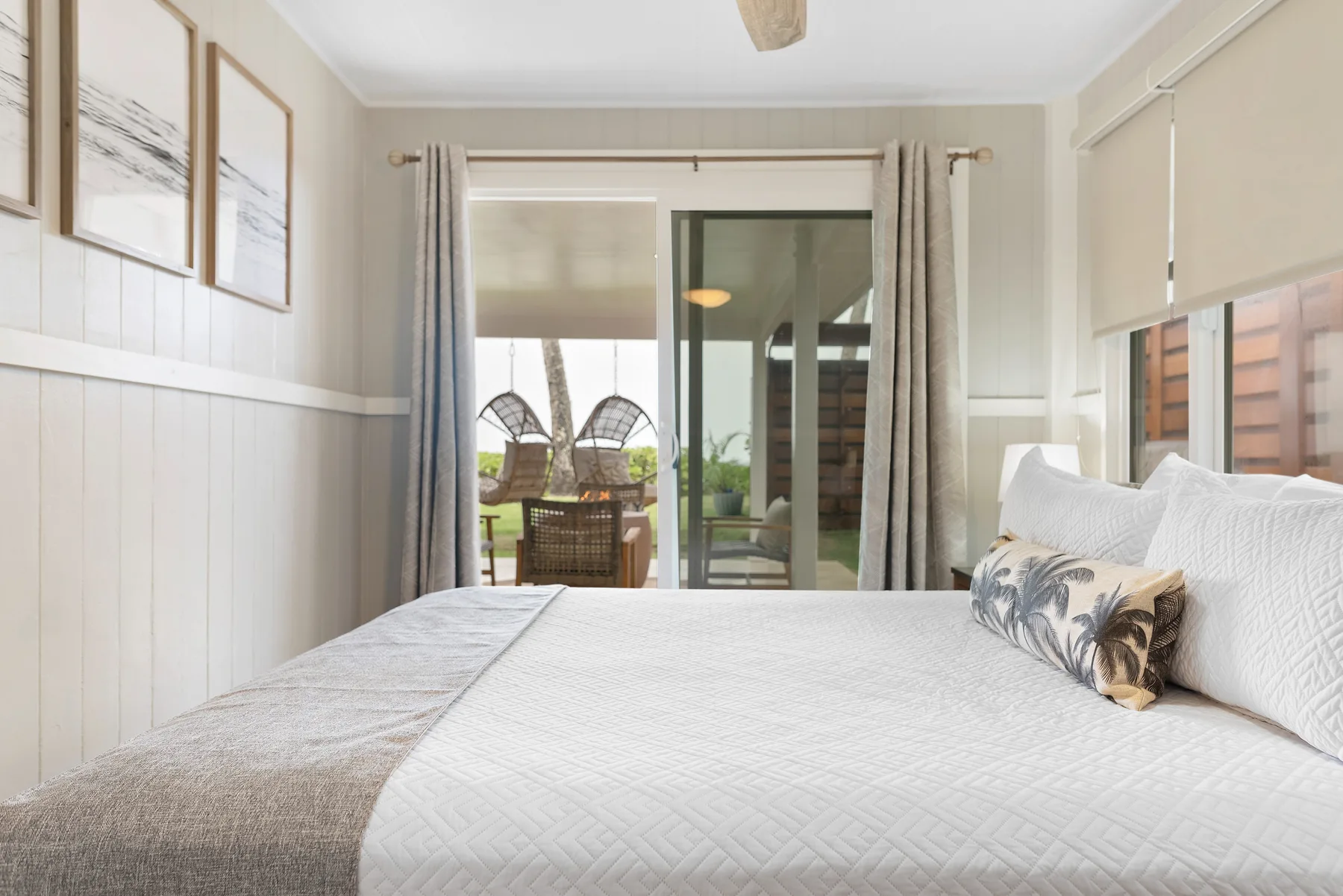 Un dormitorio luminoso con una cama grande y puertas corredizas de vidrio que dan a un patio.