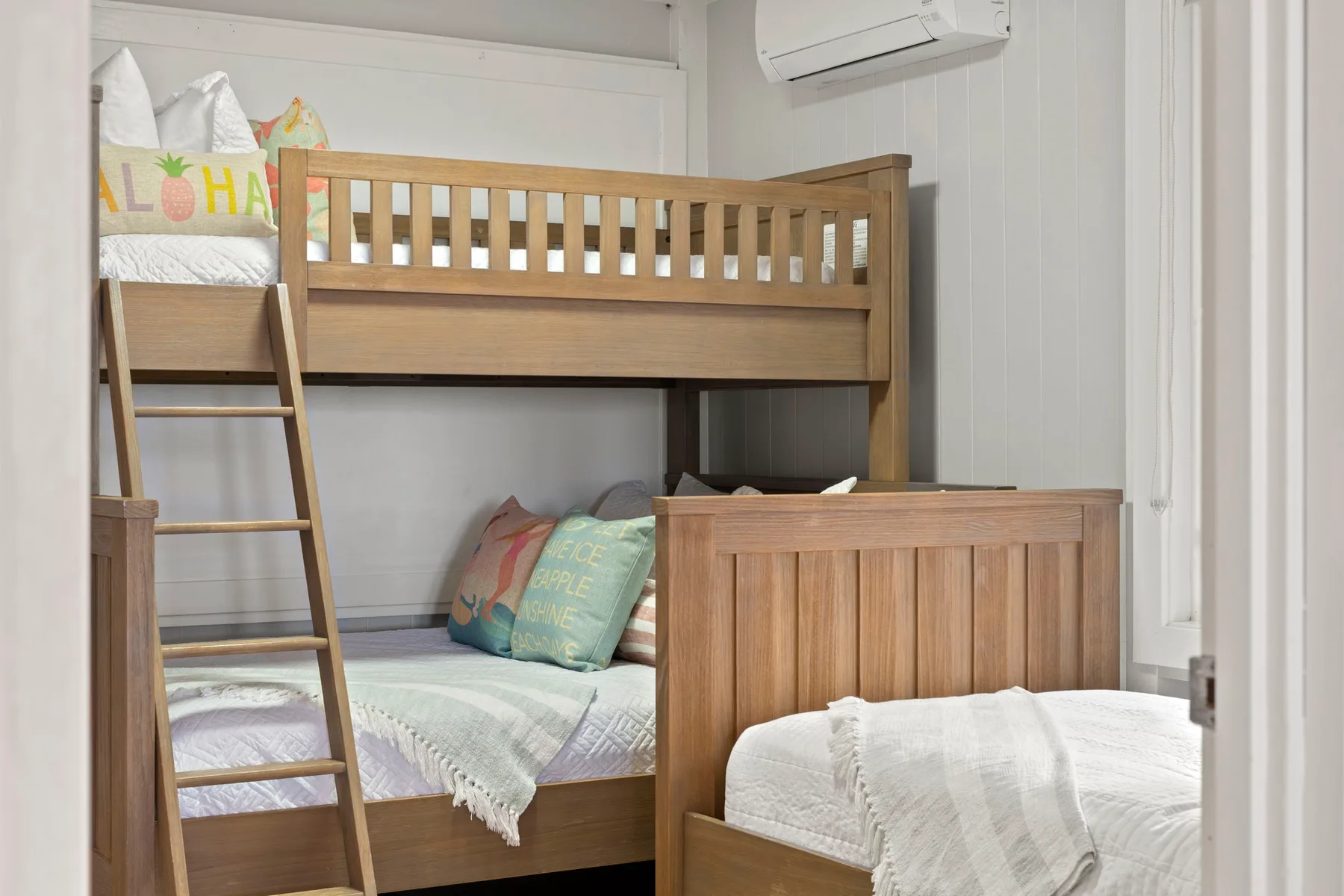 Un dormitorio con una litera de madera y una cama inferior en primer plano.