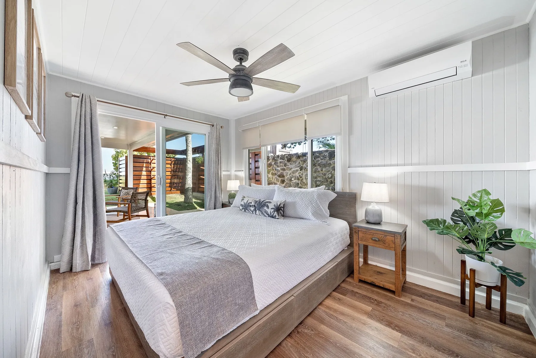 Un dormitorio luminoso con una cama grande, ventilador de techo y puertas corredizas de vidrio.