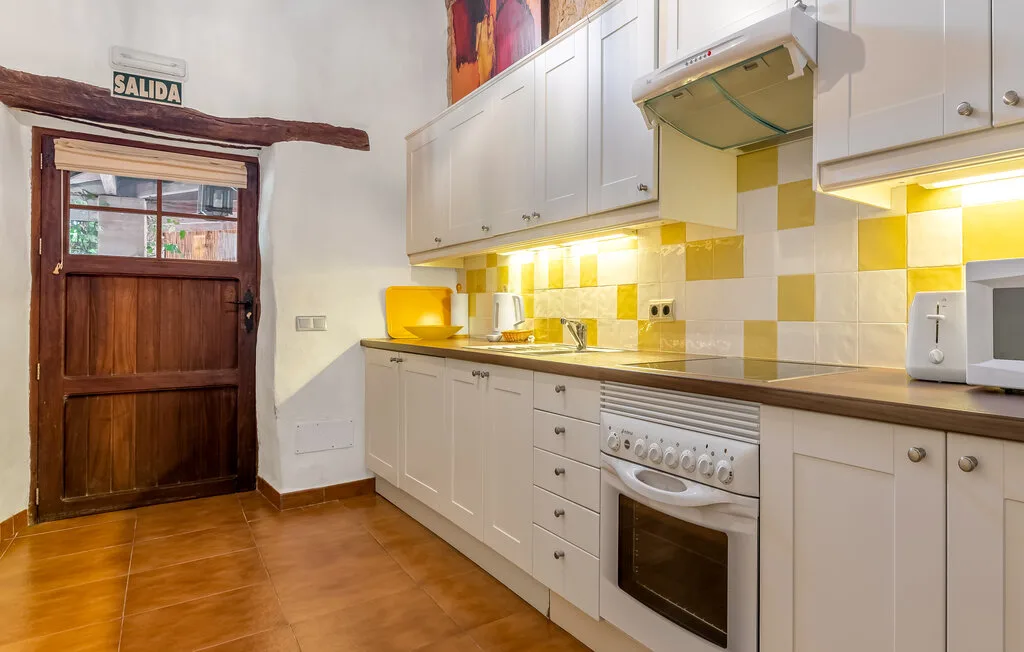 A kitchen with white cabinets, a tiled backsplash, and a wooden door.