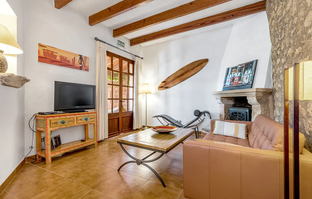 Una sala de estar con asientos, un televisor y vigas de madera a la vista.