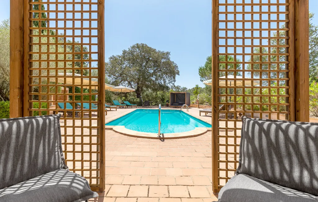 An outdoor swimming pool is framed by wooden lattice panels and seating.