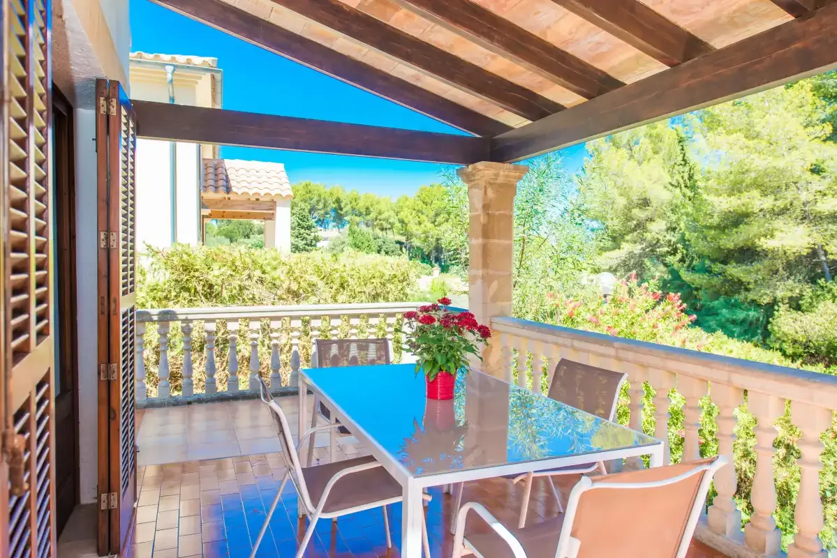 Comedor exterior cubierto con una mesa y sillas, con vistas al jardín.