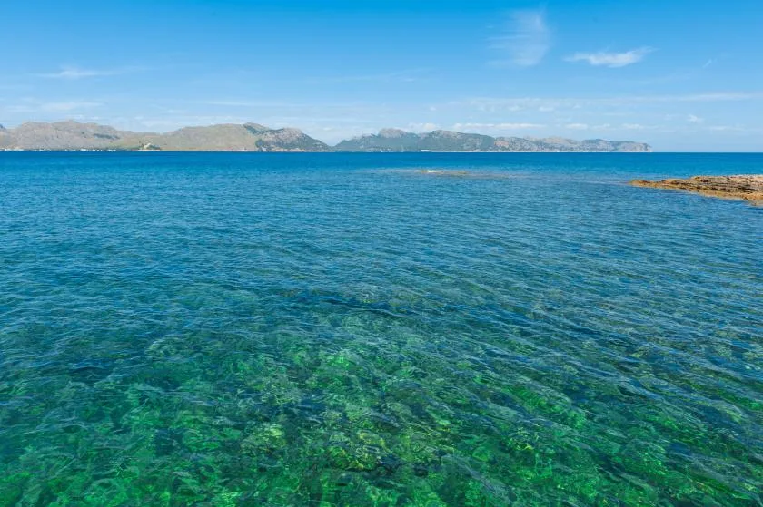 Un paisaje costero con aguas azules y colinas a lo lejos.