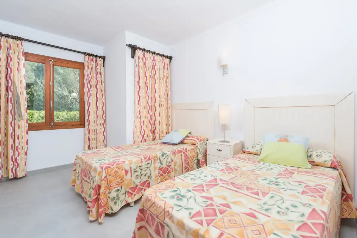 Un dormitorio con dos camas cubiertas con ropa de cama estampada y colorida.