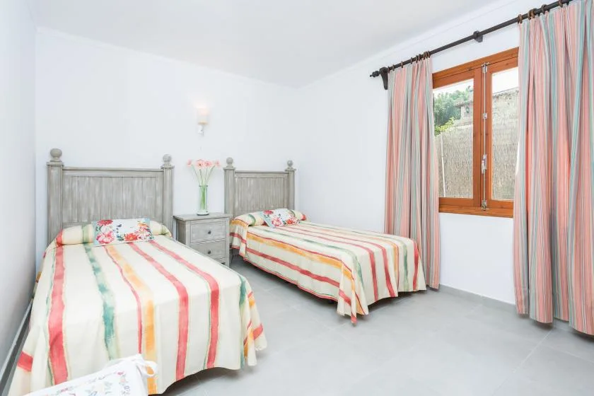 Un dormitorio luminoso con dos camas y una ventana enmarcada por cortinas a rayas.
