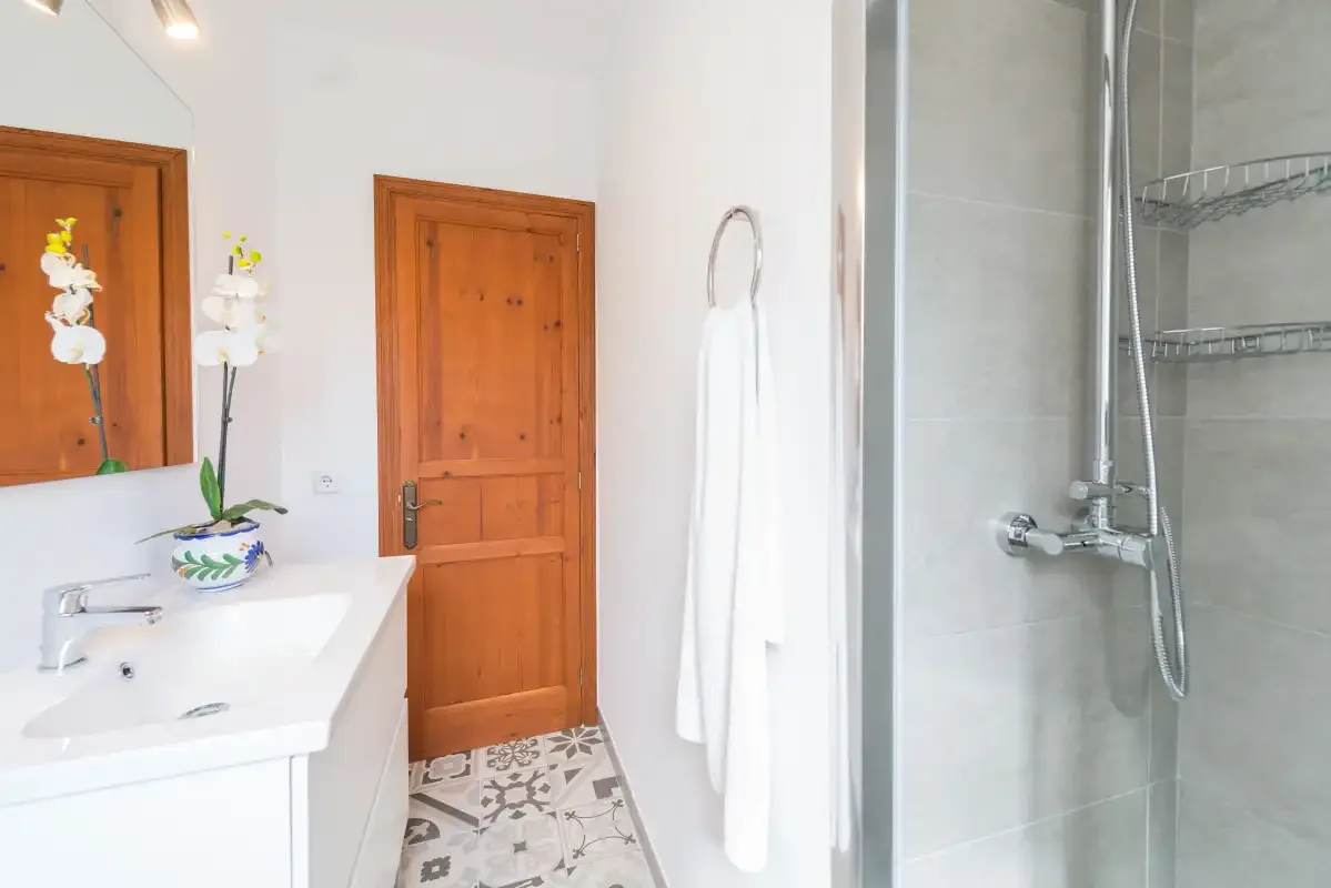 Un baño luminoso con lavabo, puerta de madera y ducha de cristal.