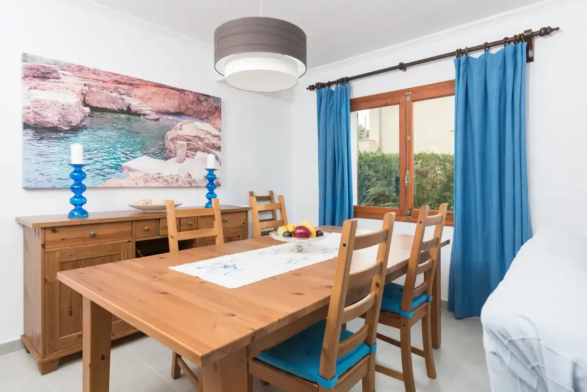 Comedor con una mesa de madera y cortinas azules junto a la ventana.