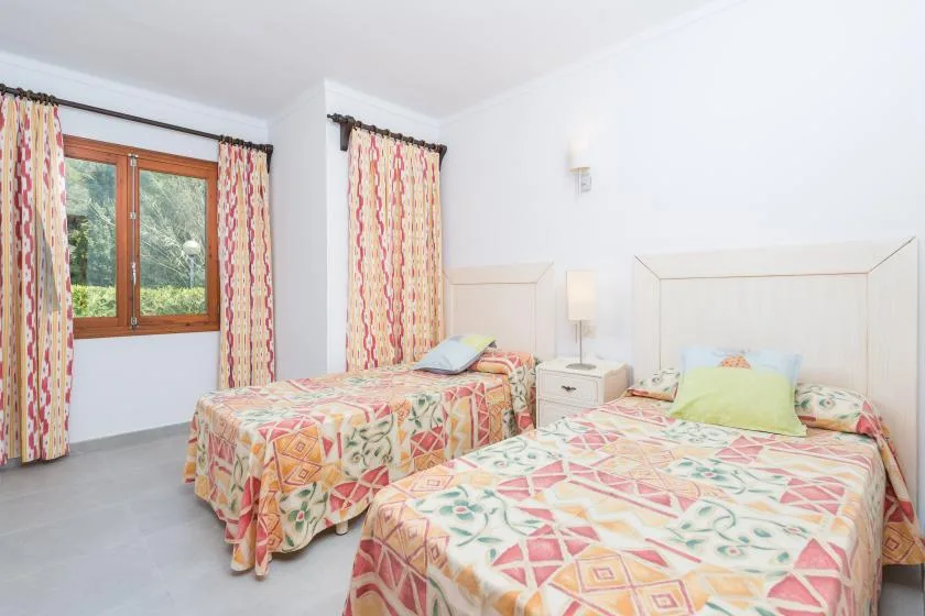 Dormitorio con dos camas vestidas con ropa de cama estampada y colorida.
