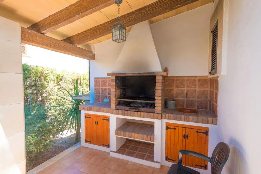 Una zona de cocina exterior cubierta con una barbacoa de ladrillo y armarios de madera.