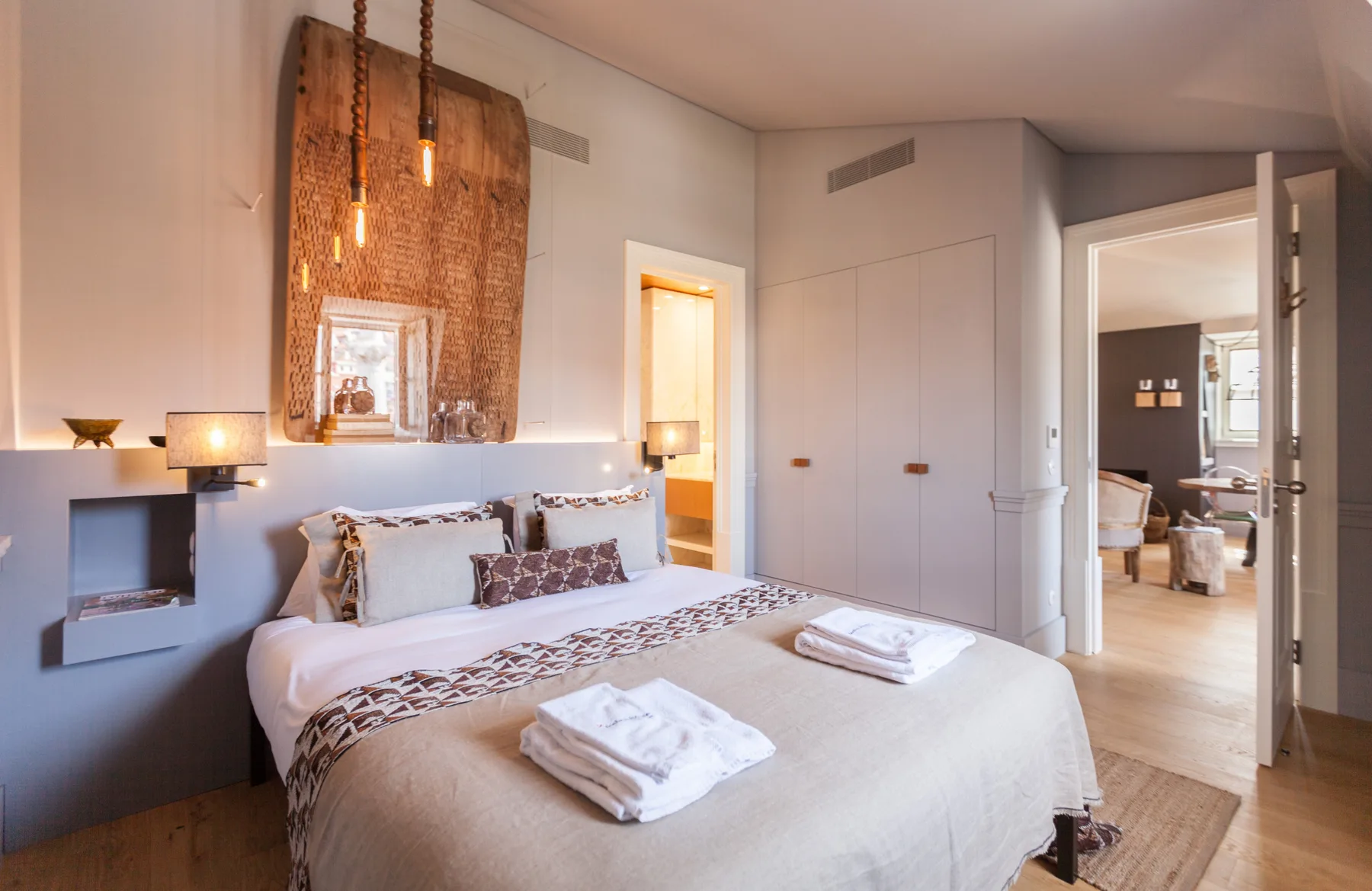 Un dormitorio con una cama, luces colgantes y una puerta abierta.