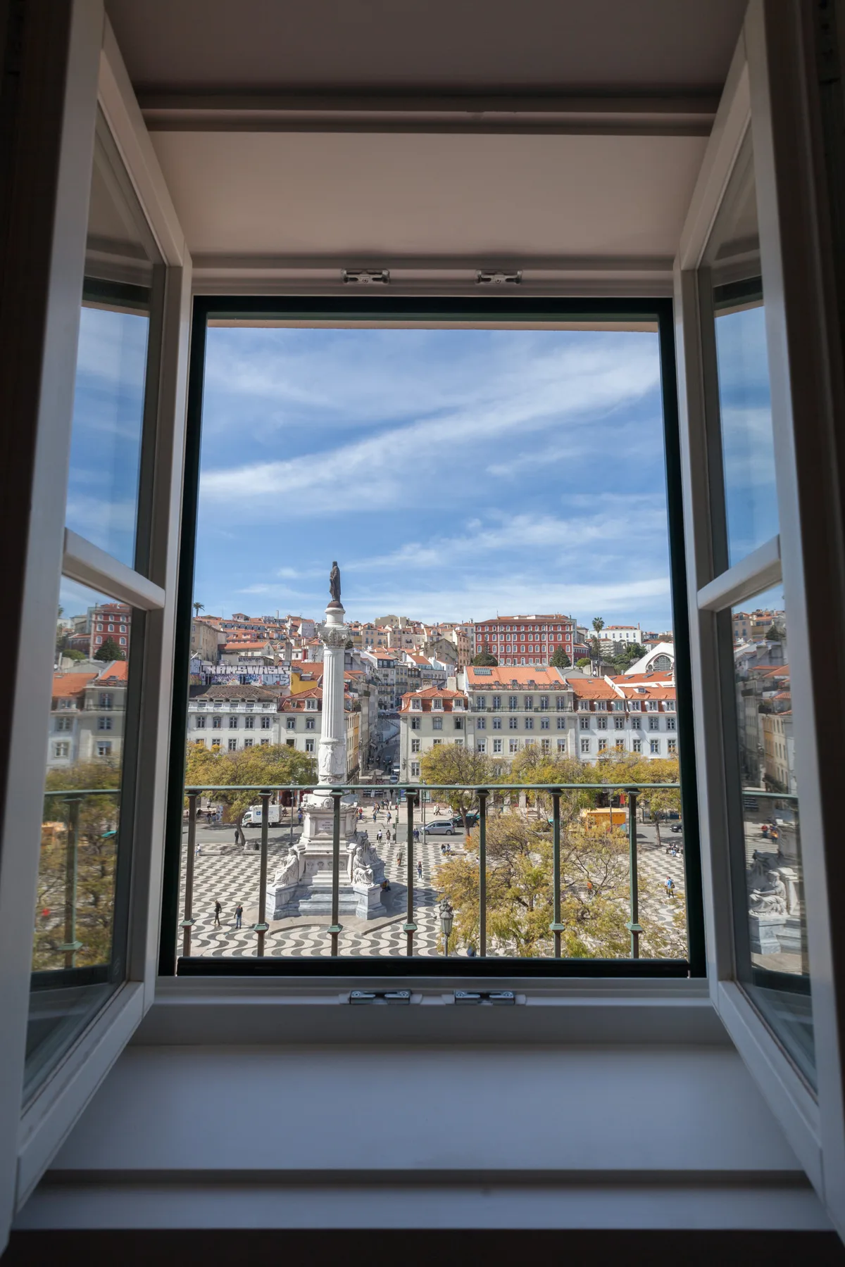 Una ventana abierta enmarca una plaza y los edificios circundantes.