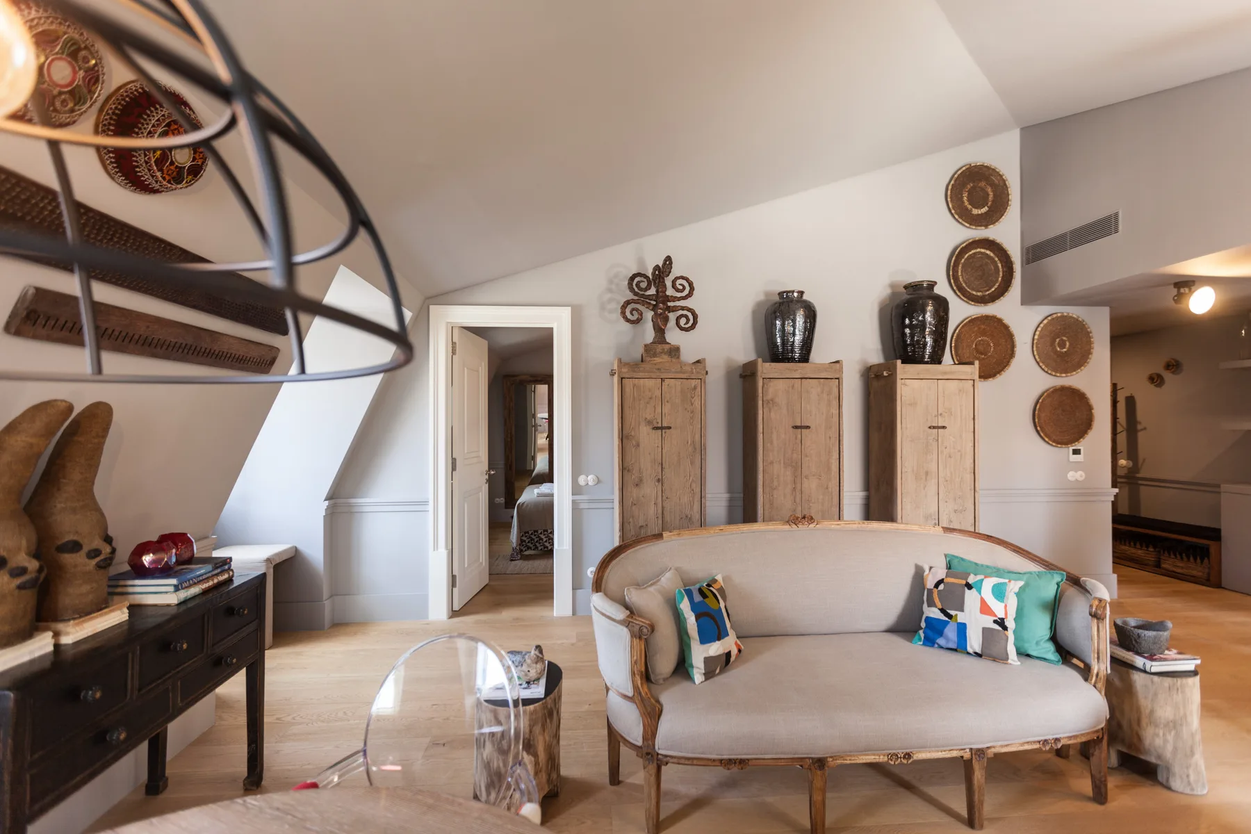 Una sala amueblada con un sofá curvo, armarios y platos decorativos en la pared.