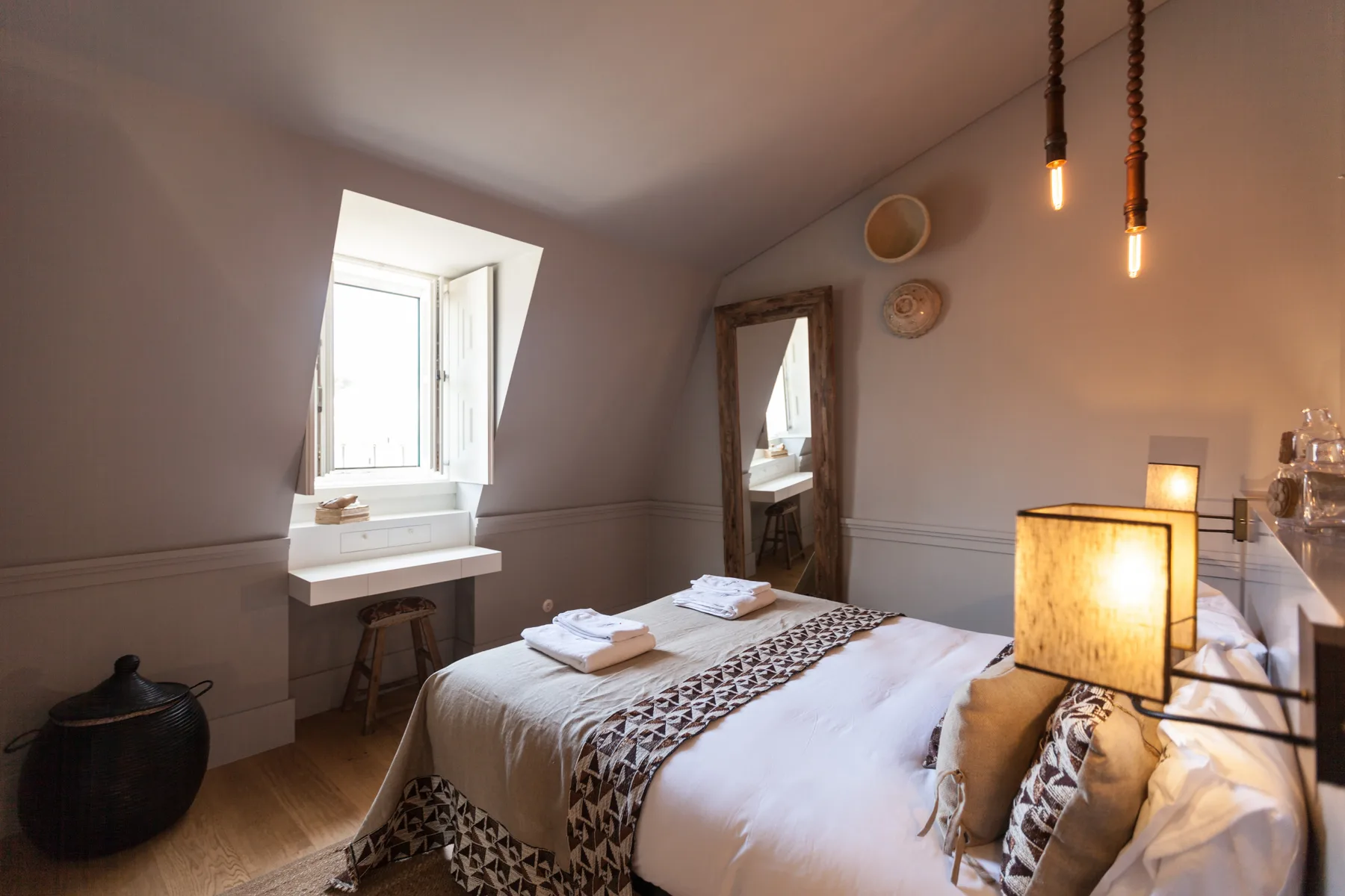 A bedroom with a neatly made bed beneath a sloped ceiling.