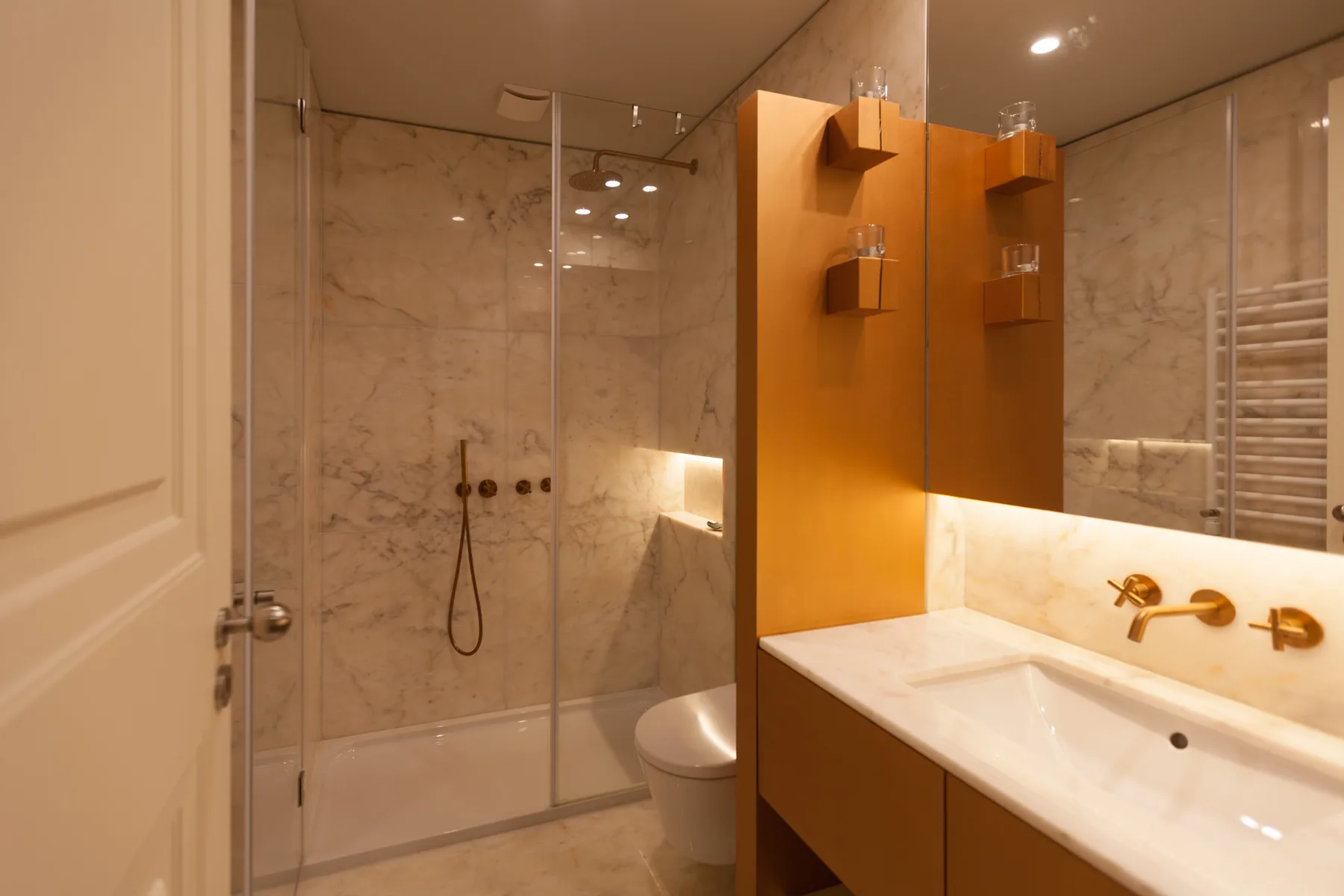 Un baño con una ducha de vidrio y un lavabo junto a un espejo grande.