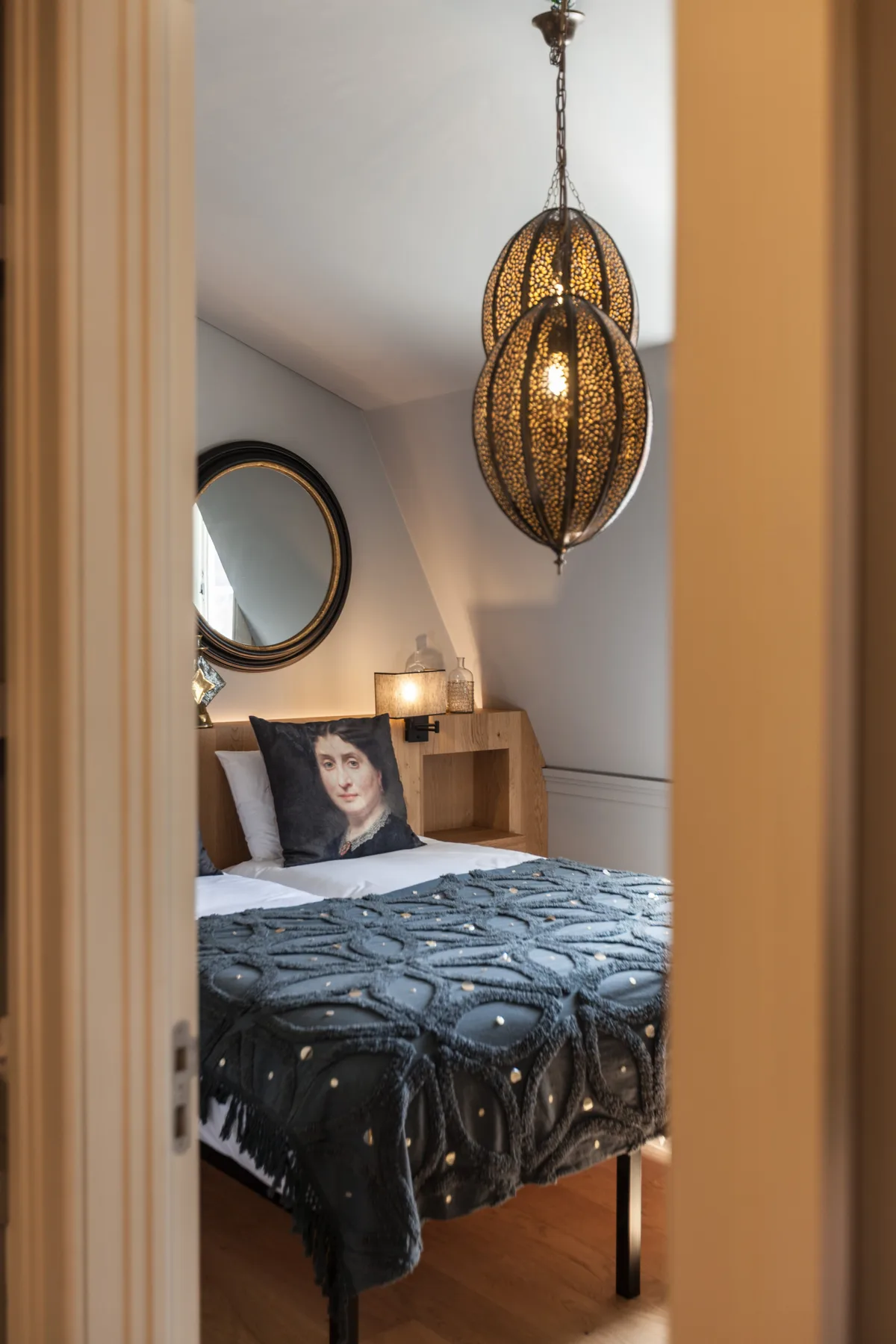 Un dormitorio con una colcha estampada y una lámpara colgante.