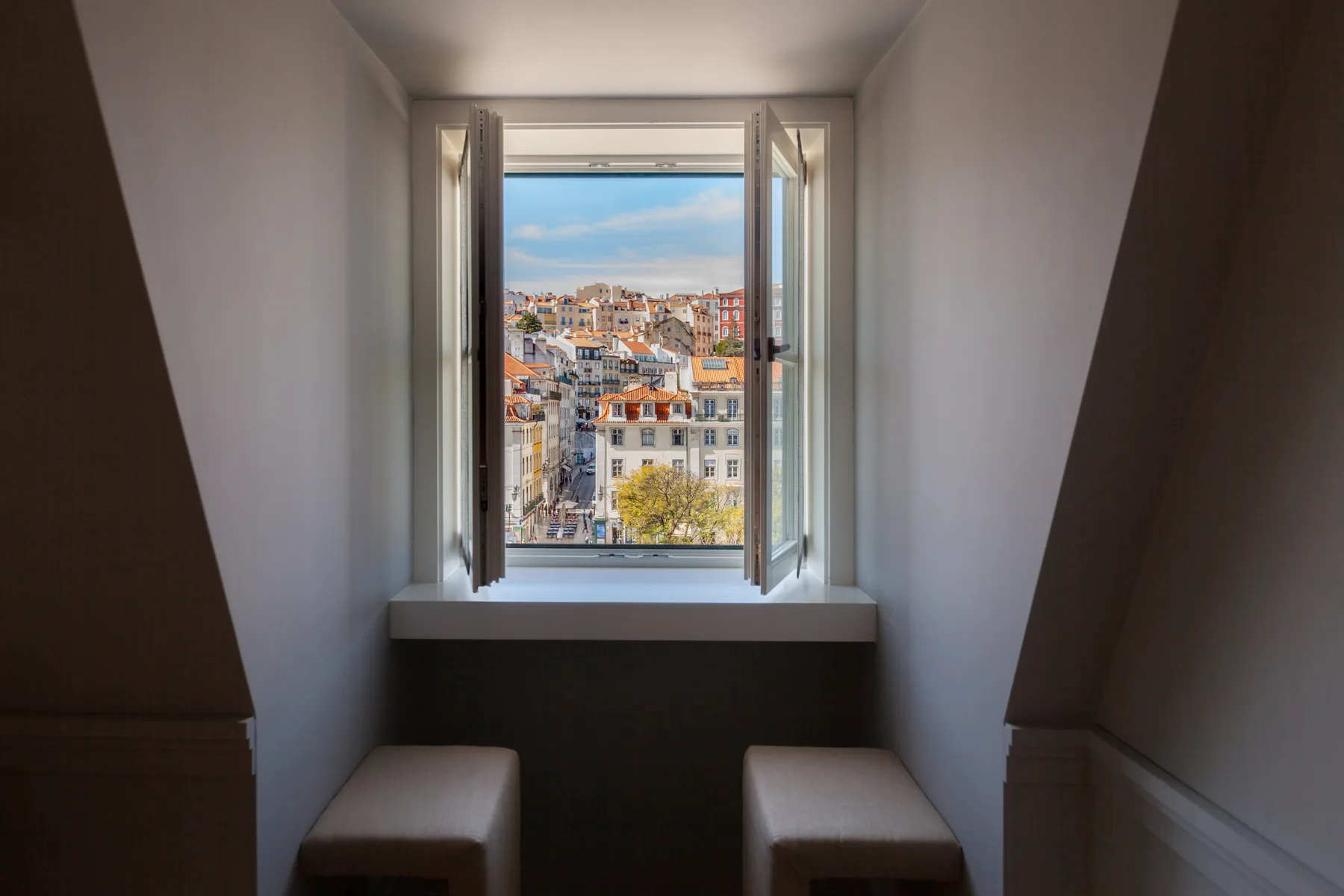 Un rincón junto a la ventana enmarca tejados de Lisboa y colinas a lo lejos.
