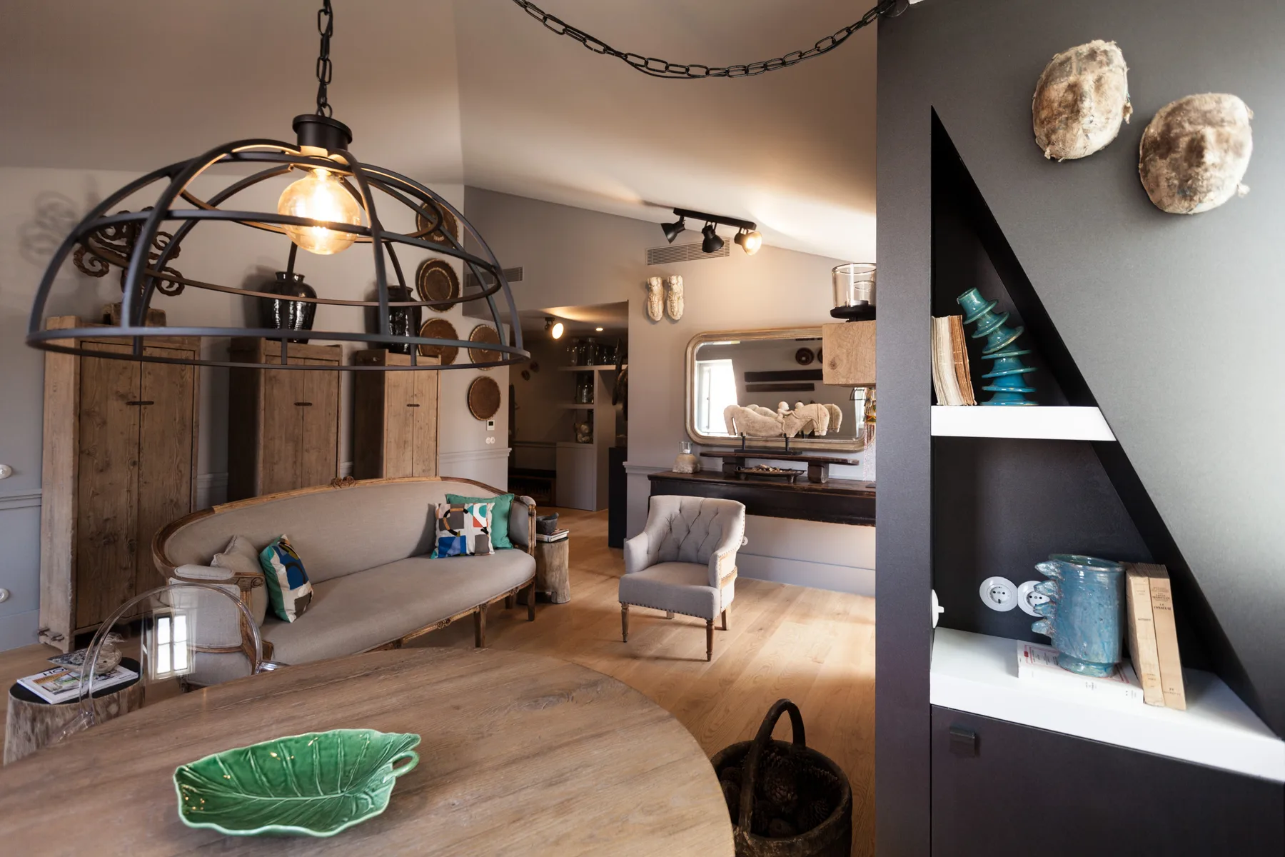 Sala de estar con asientos, suelo de madera y una estantería abierta.