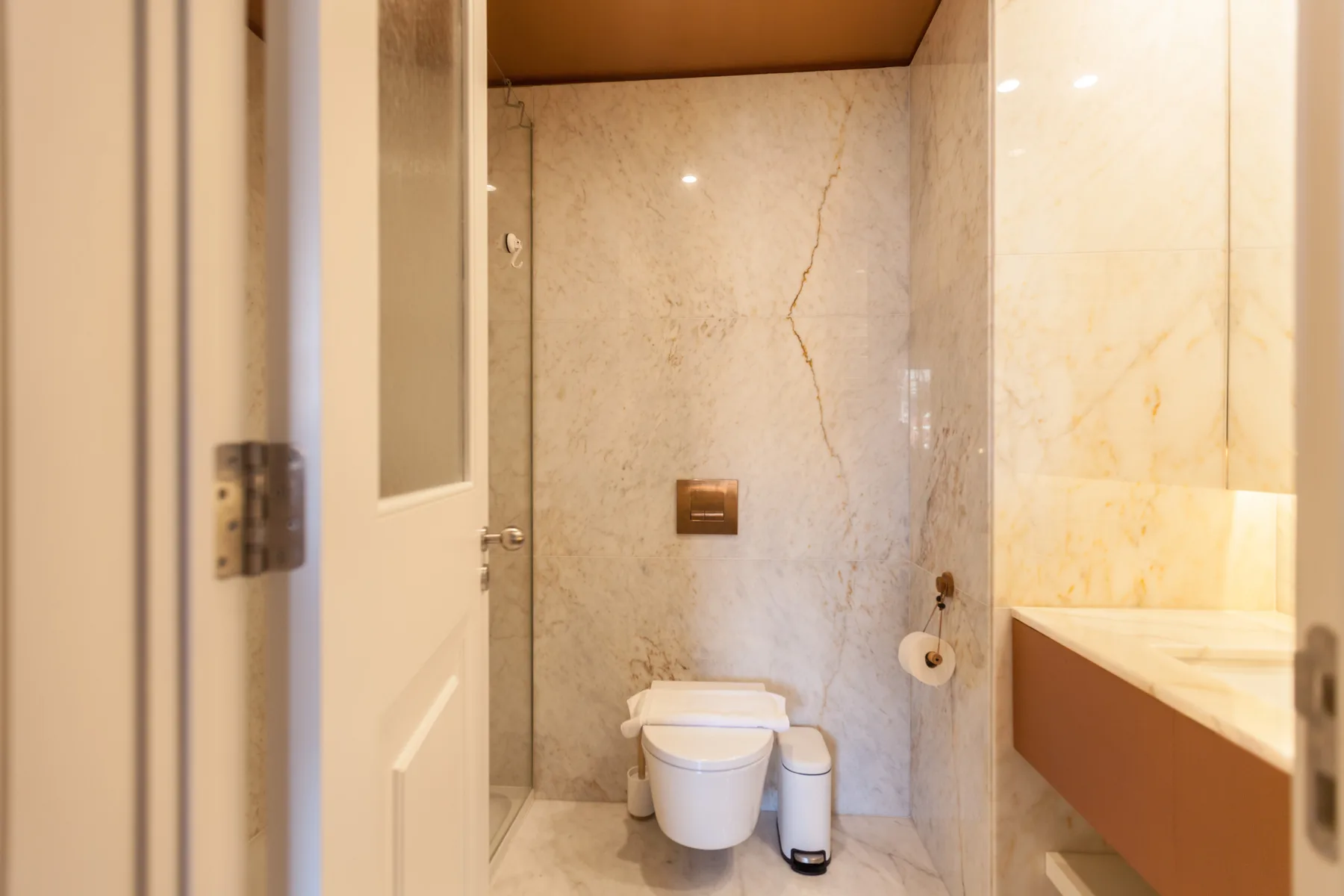 Un baño con inodoro, portarrollos de papel higiénico y tocador.