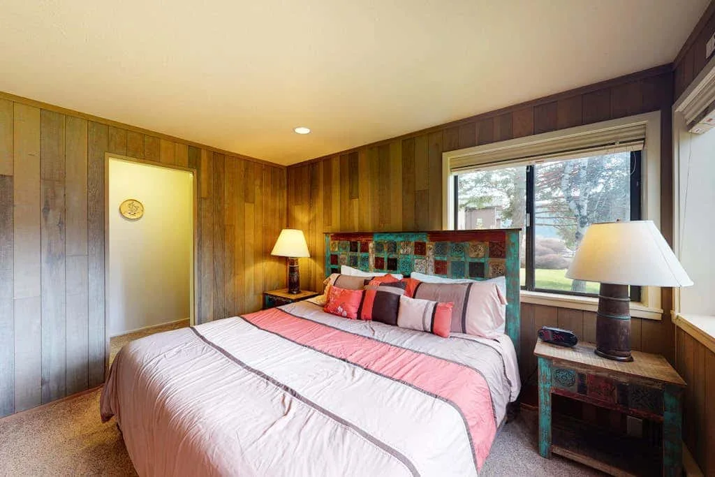 Un dormitorio con una cama bien tendida y una ventana grande.