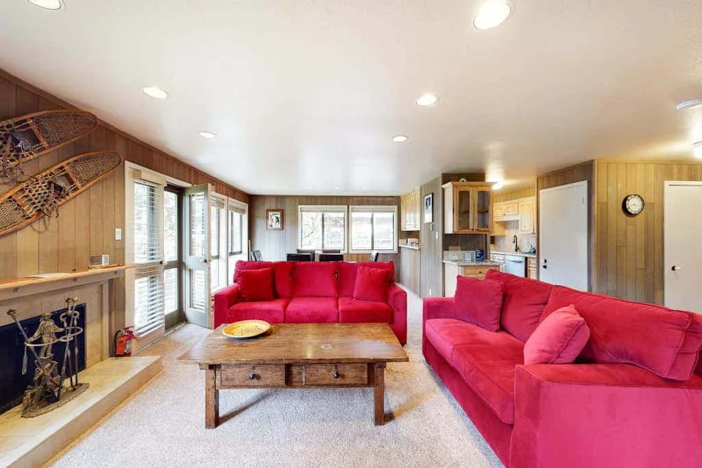 A living room with red seating, a wooden coffee table, and a fireplace.
