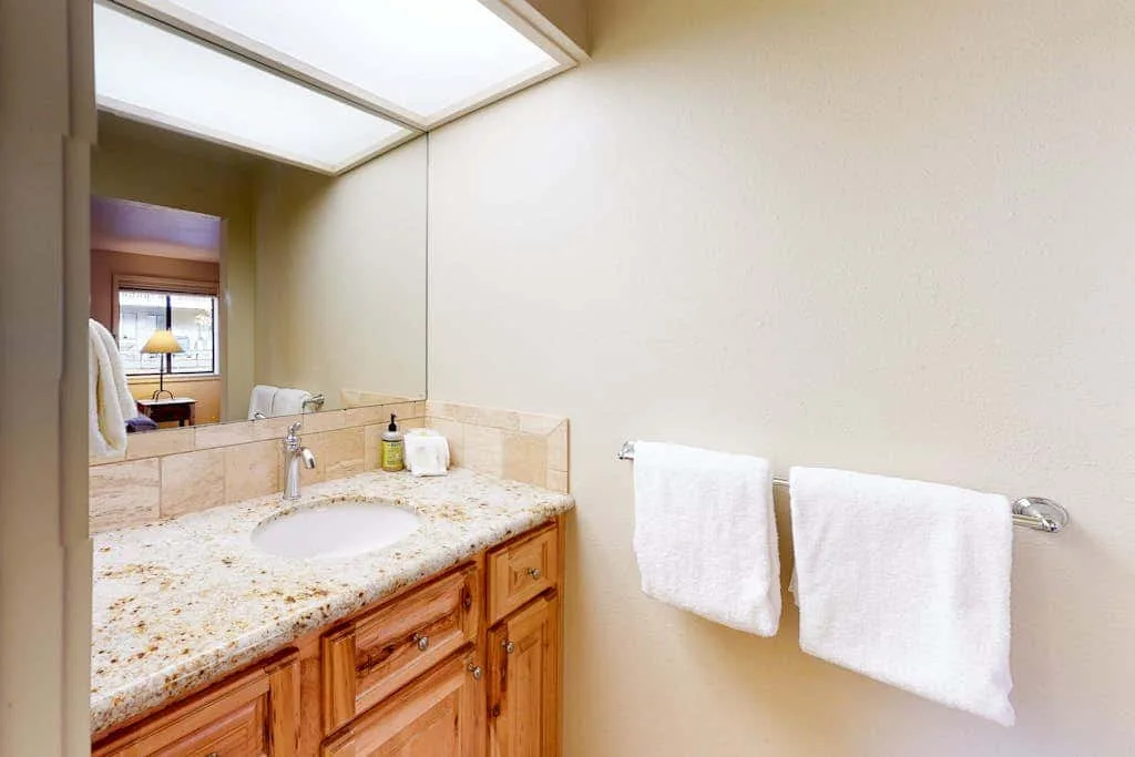 Vanidad de baño con lavabo, espejo y toallas en la pared.