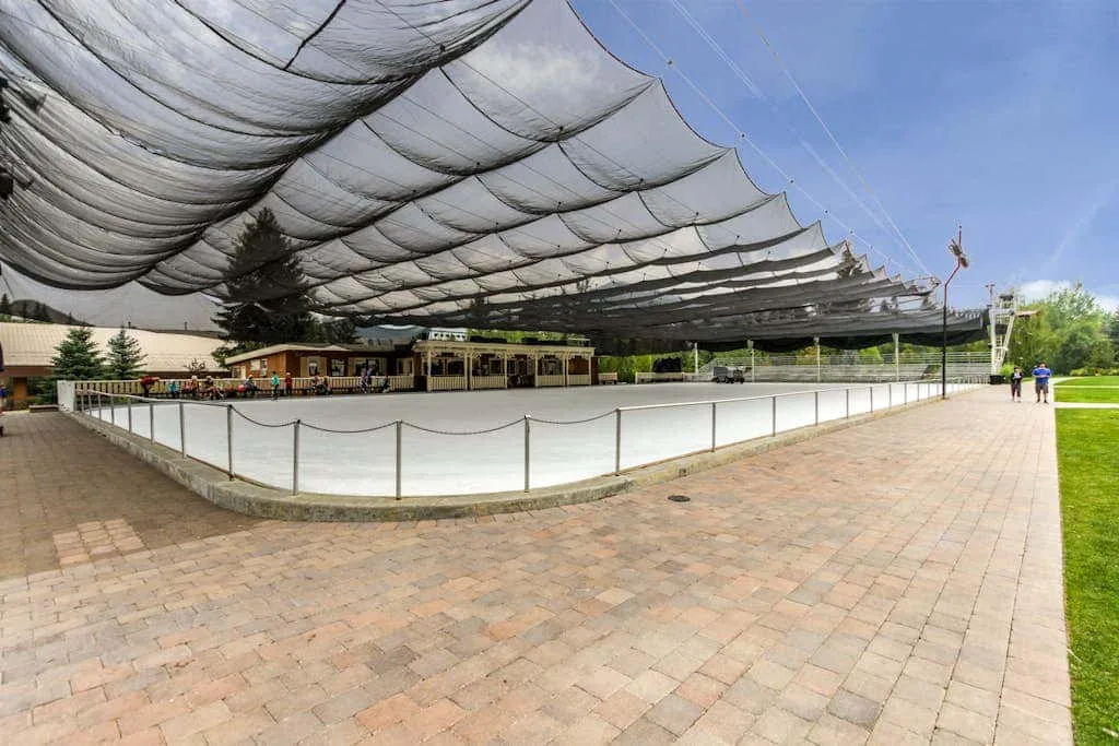 Una pista de hielo al aire libre está bajo grandes toldos, junto a paseos pavimentados.
