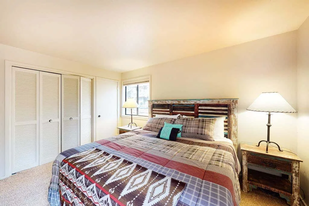 Un dormitorio con una colcha estampada, una mesita de noche y lámparas.