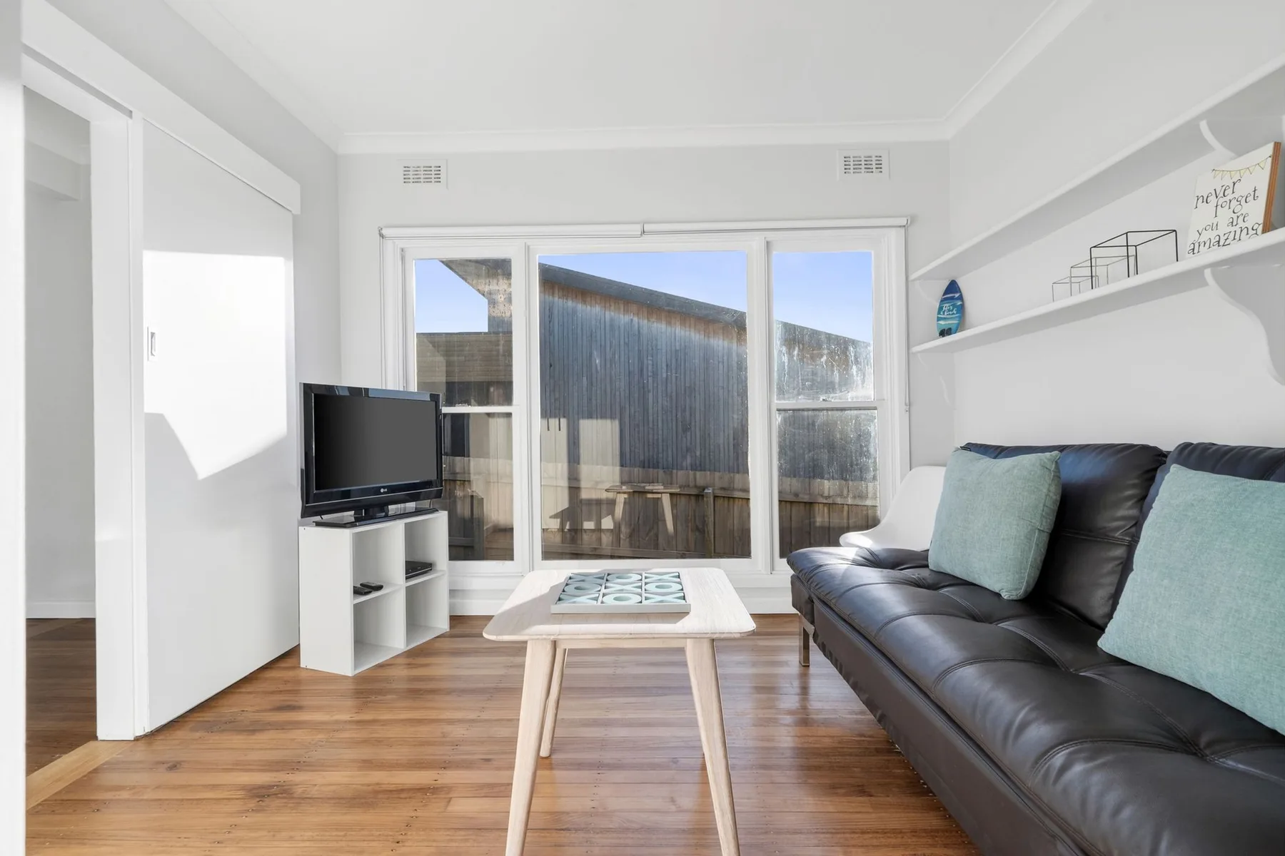 A bright living room with seating, a television, and sliding glass doors.