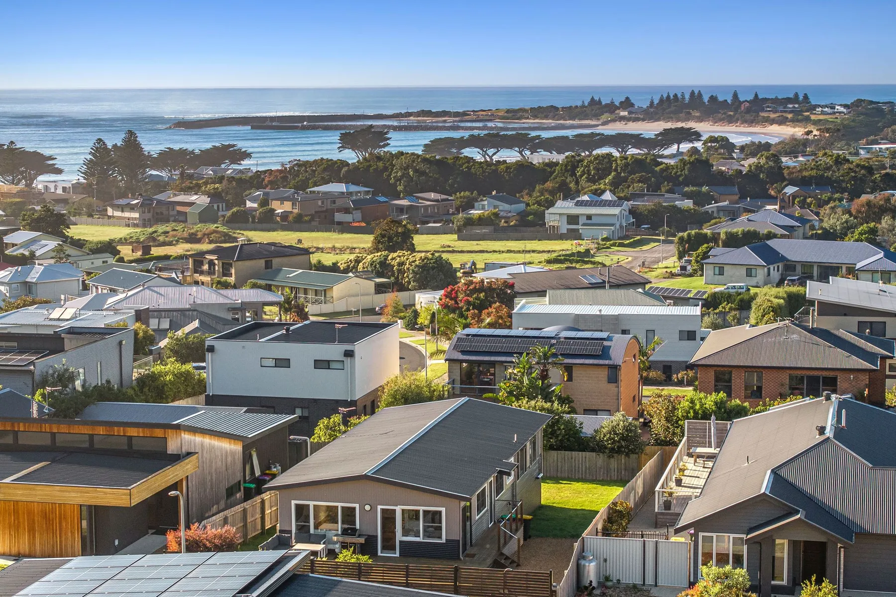 A coastal neighborhood overlooks the ocean and a rocky shoreline.