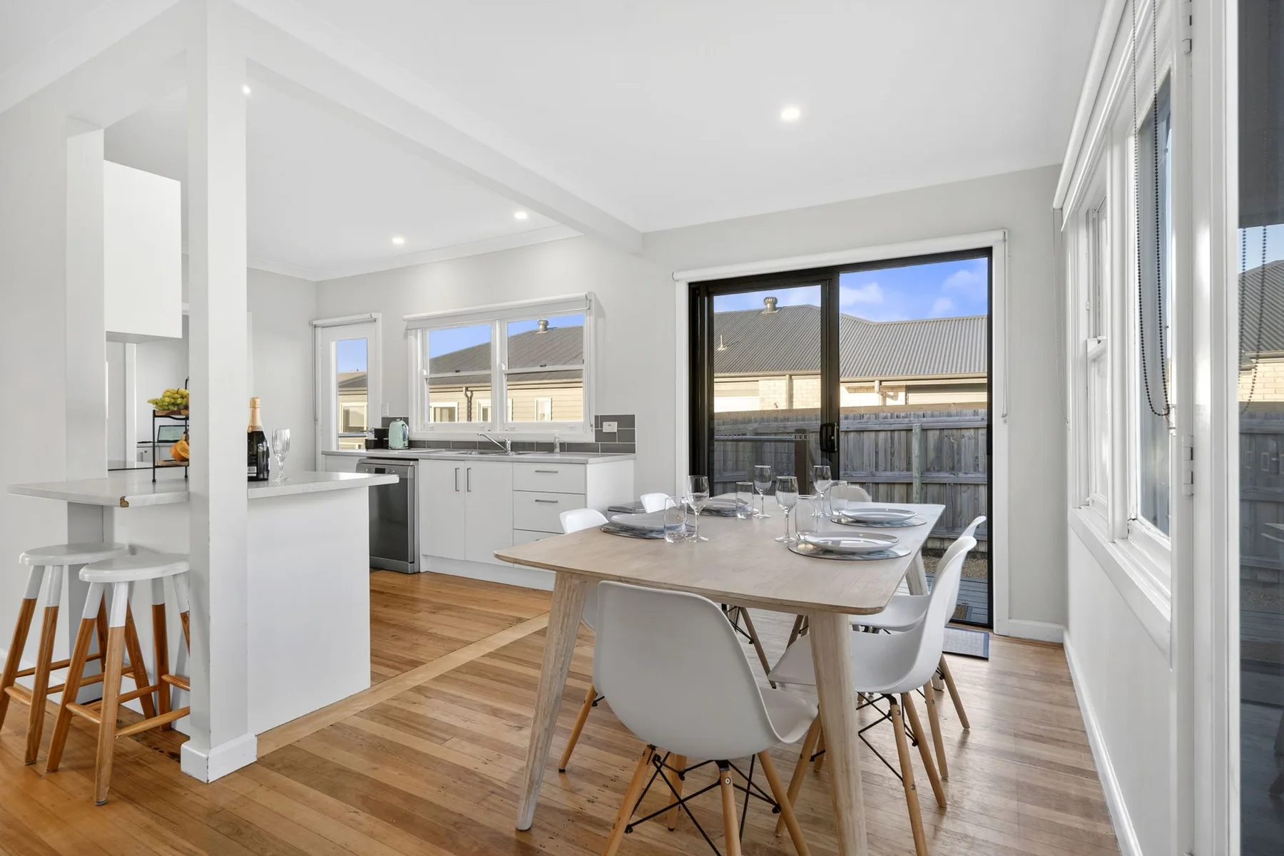 A bright kitchen and dining area with a table beside large windows.