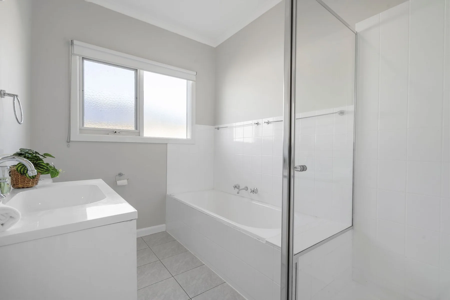 A bright bathroom with a bathtub, shower, and window.