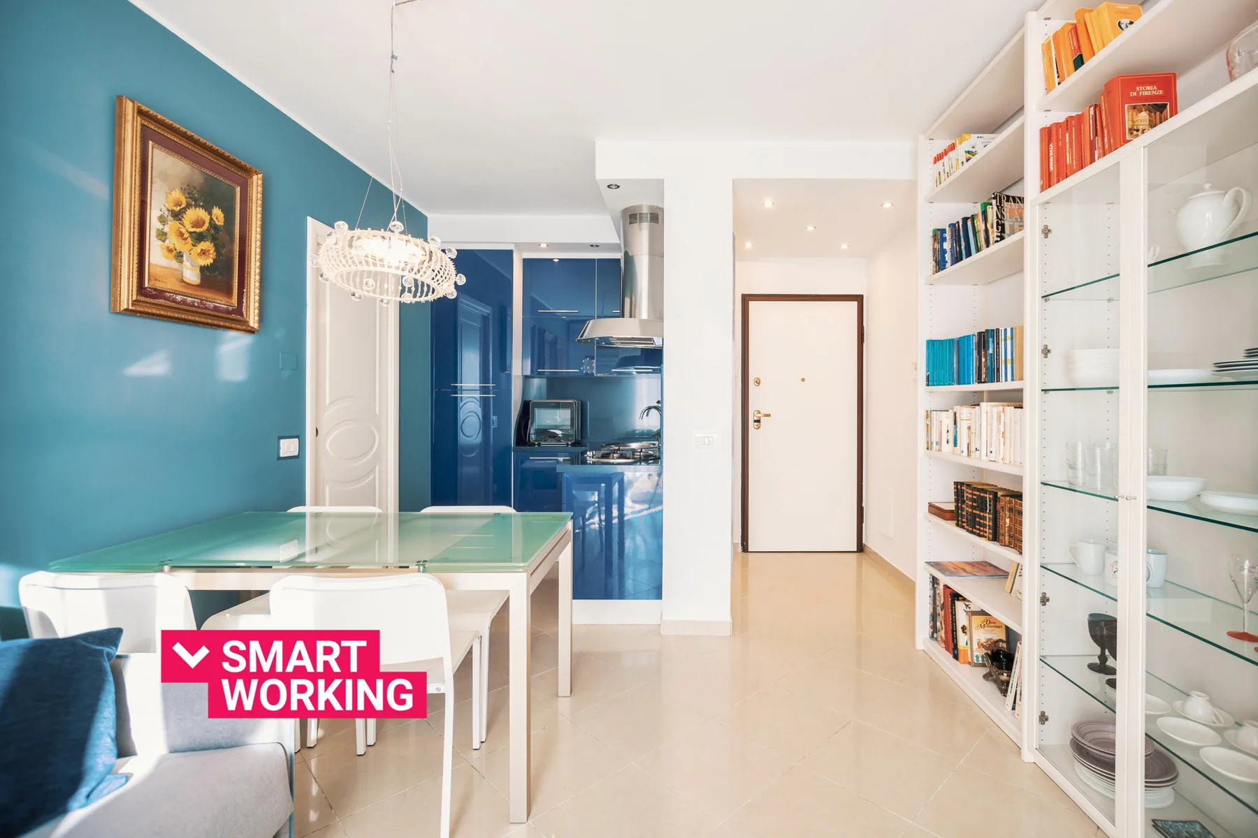 A bright dining area with a glass table beside a wall of bookshelves.