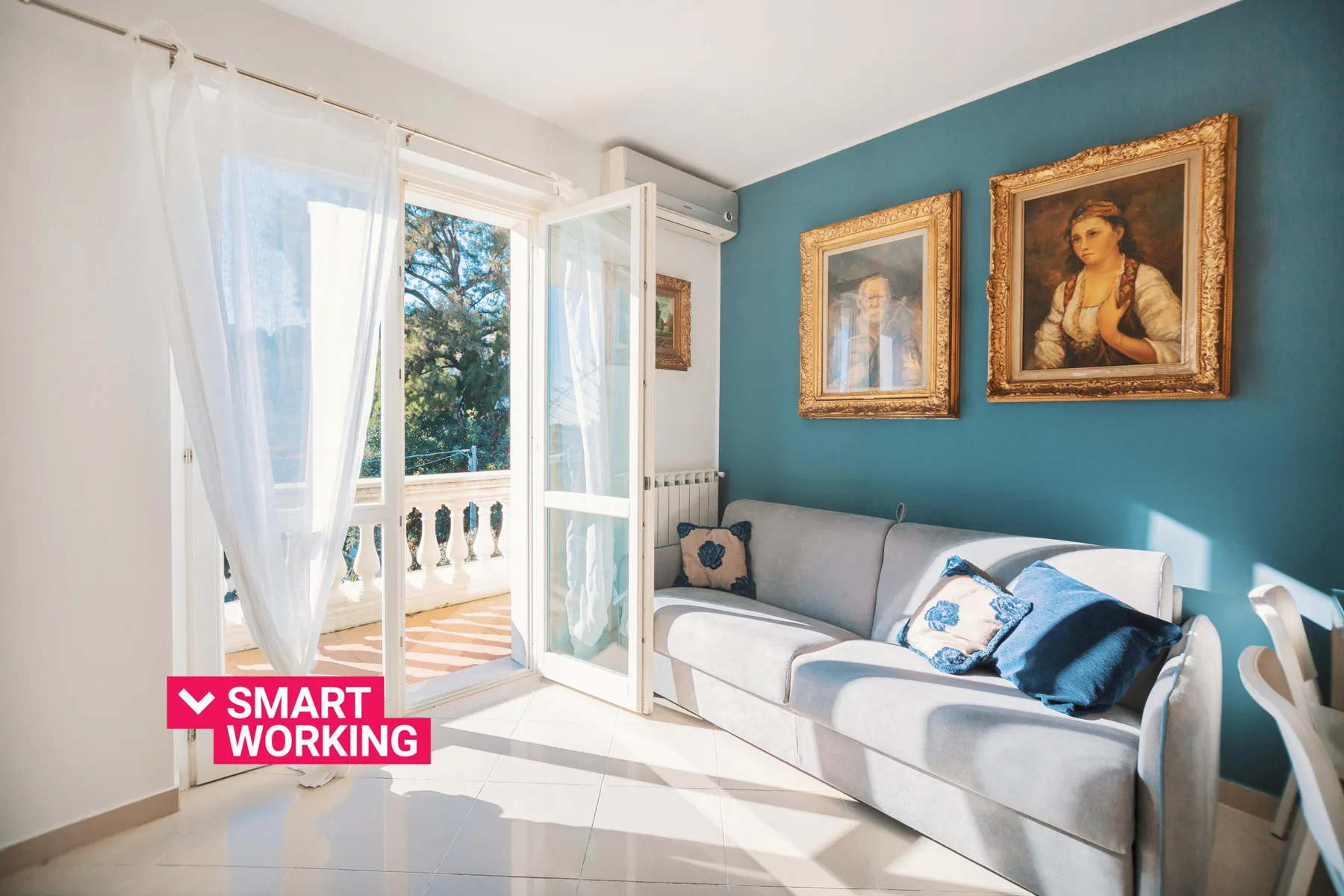 A bright living room with a gray seating area and open balcony doors.