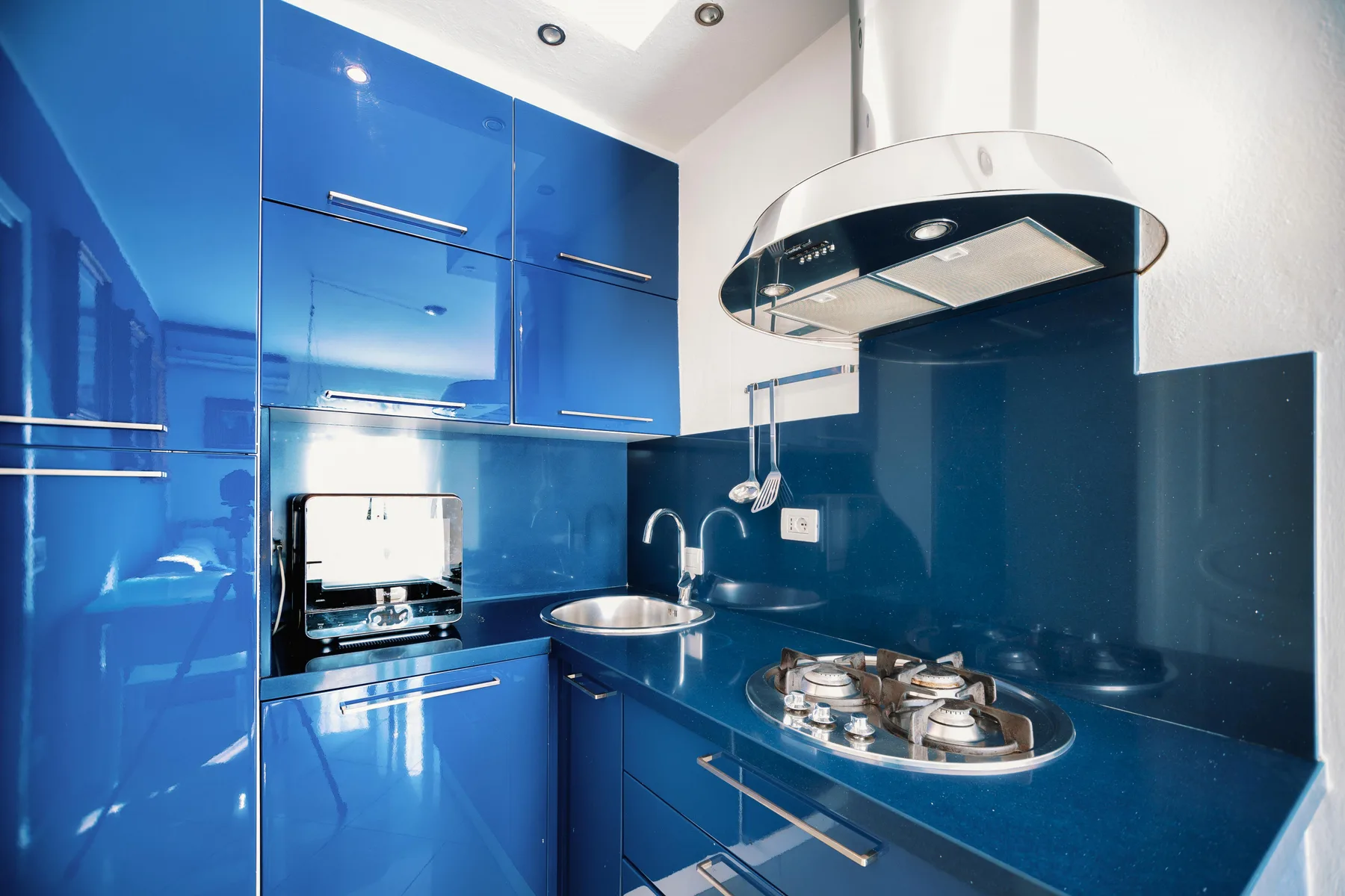 A modern blue kitchen with glossy cabinets and a cooktop.