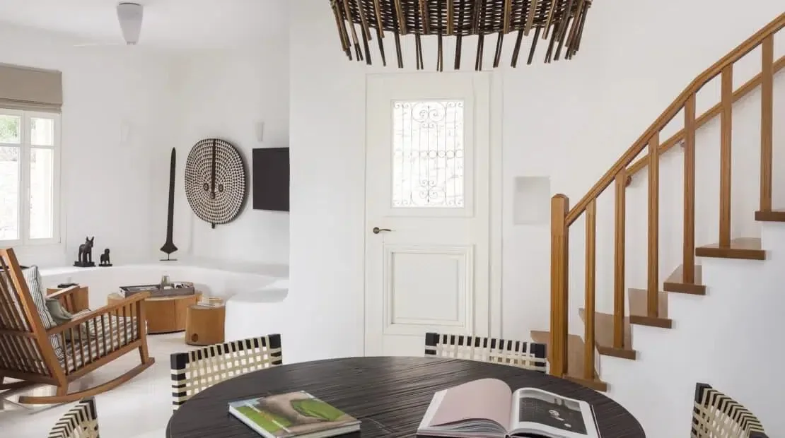 Un comedor luminoso con una mesa redonda y una escalera.