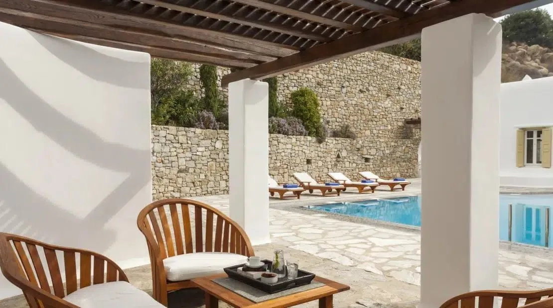 Un patio sombreado da a una piscina y un patio de piedra.